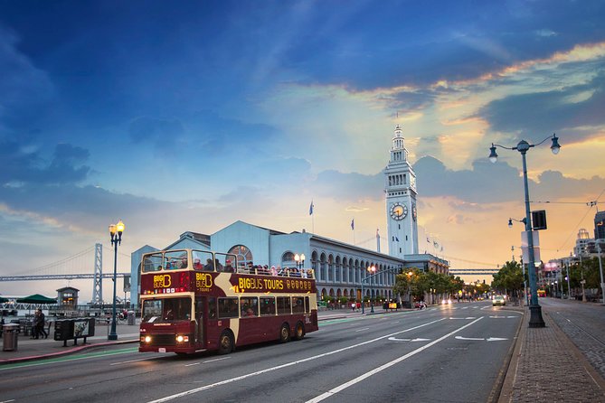 An open-top double-decker sightseeing bus on the road with the Golden Gate Bridge behind it